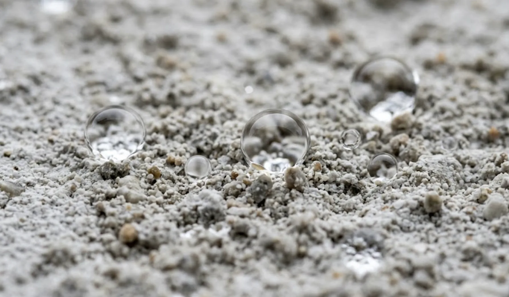 Macro photo d'un enduit de façade propre montrant l'effet perlant des gouttes après application d'hydrofuge